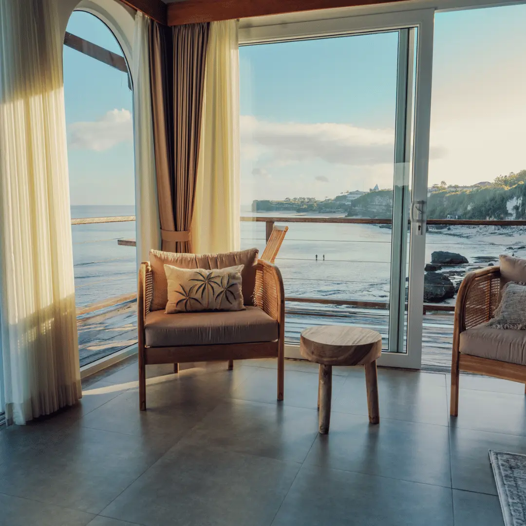 Cozy seating area with reclaimed wood table, chairs, and coastal view in a suite at Sabbia by Nyoman & Nyoman, Bingin Beach surf hotel.